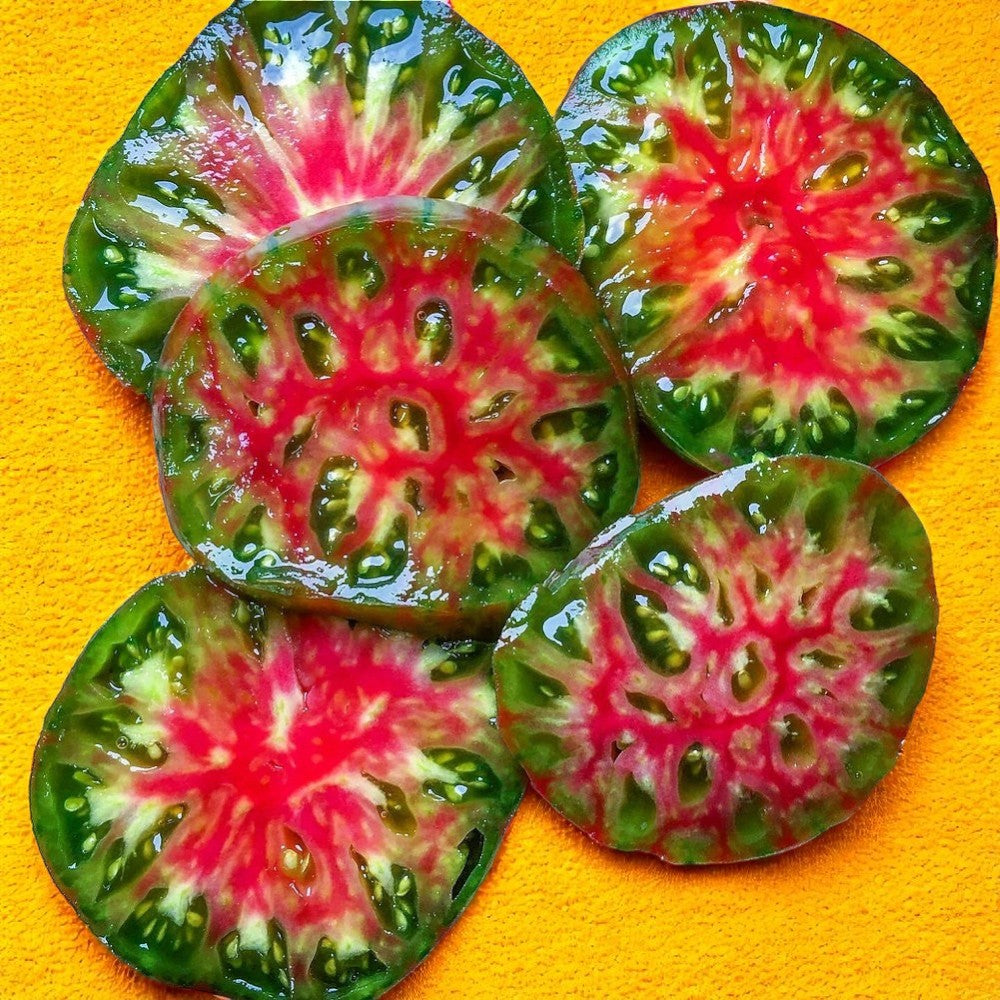 Sliced watermelon Tomato Ananas Noir with pink and green tomato on a yellow background